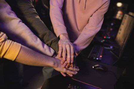 Cropped view of multiethnic team holding hands in cyber club 