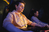 Young man using keyboard near blurred multiracial friend in gaming club  t-shirt #650690272