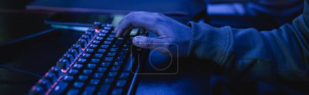 Cropped view of gamer using keyboard in gaming club with blue lighting, banner  tote bag #650690340