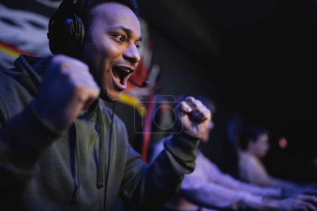 Photo for Excited indian gamer in headphones doing yes gesture in cyber club - Royalty Free Image
