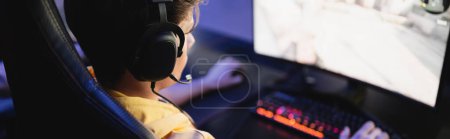 Téléchargez les photos : Gamer dans les écouteurs jouer à un jeu vidéo sur ordinateur dans le cyber-club, bannière - en image libre de droit