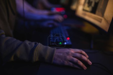 Cropped view of gamer sitting near blurred computer in cyber club 