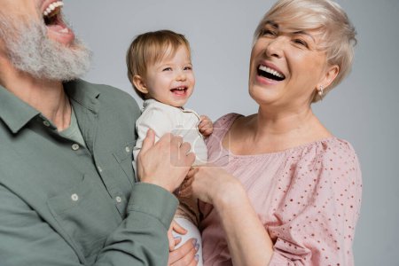 Photo for Overjoyed couple laughing near beloved granddaughter isolated on grey - Royalty Free Image