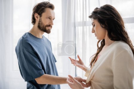 Angry man pulling clothes of blurred girlfriend during relationship difficulties at home 
