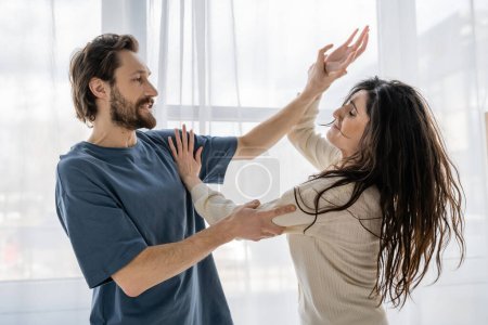 Angry man beating worried girlfriend during conflict at home 