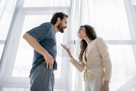 Tiefansicht einer aggressiven Frau, die während eines Konflikts zu Hause mit ihrem Freund spricht 