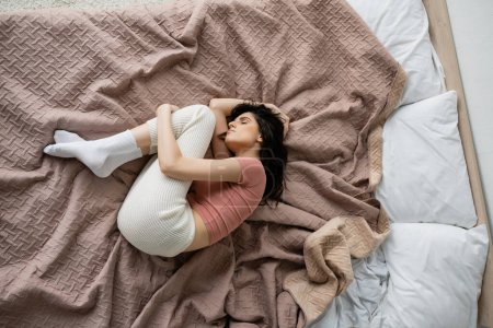 Top view of lonely woman in pajama lying on bed at home 