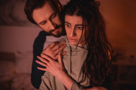 Photo for Bearded man hugging sad girlfriend at home in evening - Royalty Free Image