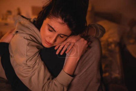Displeased woman embracing boyfriend in bedroom at night 
