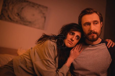 Téléchargez les photos : Triste femme étreignant petit ami barbu dans la chambre à coucher à la maison - en image libre de droit