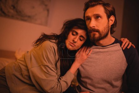 Téléchargez les photos : Brunette femme étreignant petit ami triste dans la chambre à coucher la nuit - en image libre de droit