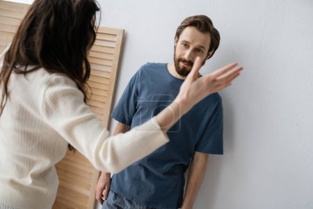 Photo for Frustrated man in pajama standing near blurred girlfriend quarrelling at home - Royalty Free Image