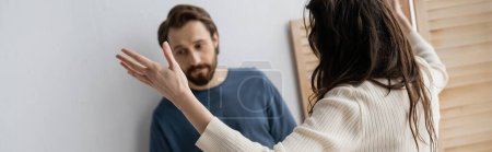 Brunette woman quarrelling with sad blurred boyfriend at home, banner 