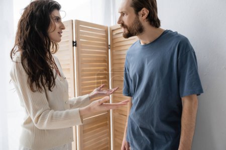 Téléchargez les photos : Vue latérale de la femme brune parlant à son petit ami en colère à la maison - en image libre de droit