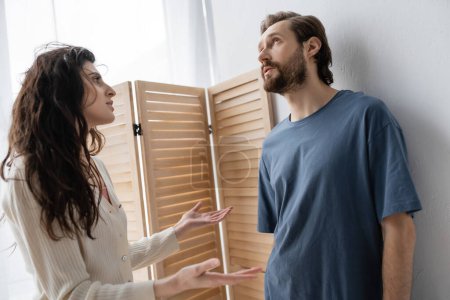 Angry woman talking to pensive boyfriend during relationship difficulties at home 