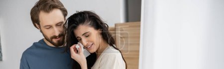 Unzufriedene Frau hält Serviette in der Hand und weint neben bärtigem Freund zu Hause, Transparent 