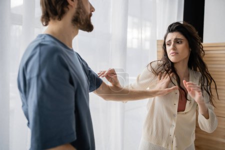 Afraid woman standing near abusive boyfriend during relationship difficulties at home 