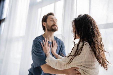 Woman pushing blurred aggressive boyfriend during quarrel at home 