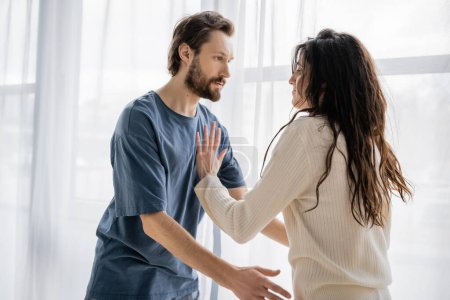 Brunette woman pushing angry boyfriend during conflict at home 