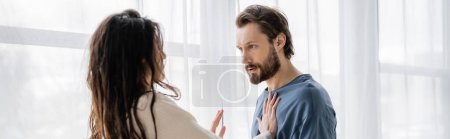 Brunette woman showing no gesture at angry boyfriend during conflict at home, banner 