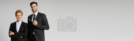 collègues d'affaires à succès en noir blazers élégants souriant à la caméra isolée sur gris, bannière
