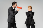 redhead manager with closed eyes covering ears with hands near boss screaming in megaphone isolated on grey Poster #652250592