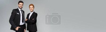 Photo for Joyful business colleagues in stylish formal wear smiling at camera isolated on grey, banner - Royalty Free Image