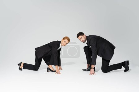 Photo for Serious business competitors in low start position looking at camera on grey background - Royalty Free Image