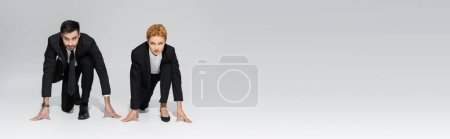 Photo for Full length of business people in black suits looking at camera and standing in low start position on grey background, banner - Royalty Free Image
