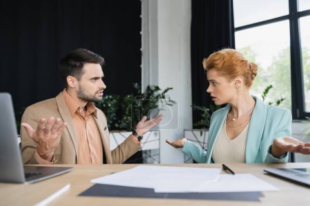 Verwirrte Manager zeigen achselzuckende Geste, während sie in der Nähe von Dokumenten im Büro reden