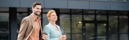 Foto de Socios de negocios felices con bebidas para llevar mirando hacia otro lado y sonriendo en la calle urbana, pancarta - Imagen libre de derechos