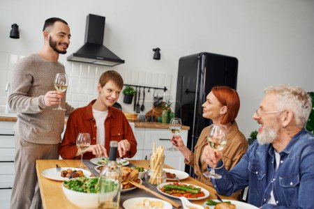 happy man toasting with wine during supper with gay partner and parents at home