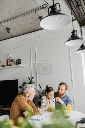 Same sex parents doing homework with preteen daughter at home 