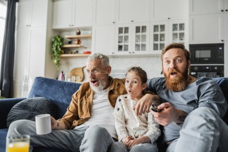 Shocked child watching tv near tattooed same sex parents at home 