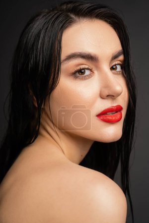 Photo for Portrait of young and pretty woman with wet brunette hair and red lips posing with bare shoulders while looking at camera after shower isolated on grey background - Royalty Free Image