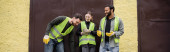 Positive multiethnic workers in high visibility vests and gloves talking while standing near door of waste disposal station outdoors, garbage sorting and recycling concept, banner  Stickers #658271698