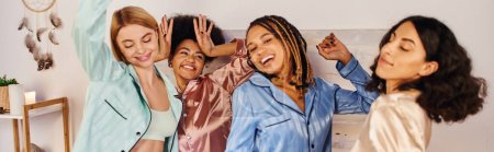 Photo for Excited and joyful multiethnic girlfriends in colorful pajama dancing and having fun together during pajama party at home, bonding time in comfortable sleepwear, banner - Royalty Free Image