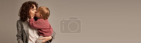 Photo for Work life balance concept, curly woman in suit kissing daughter on grey background, loving mother, balanced lifestyle, modern working woman. modern parenting, career and family, banner - Royalty Free Image