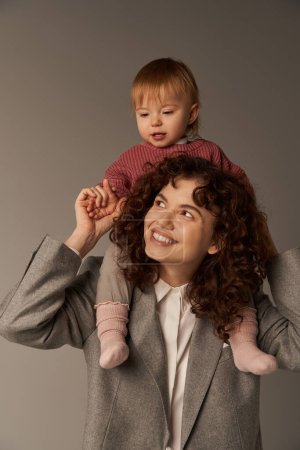 motherhood, kid on shoulders, work life balance, cheerful working mother, woman and happy daughter on grey background, work life harmony concept, loving motherhood, quality family time 