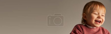 Foto de Retrato de niña linda, niño pequeño, niño feliz en traje casual sonriendo sobre fondo gris en el estudio, emoción, inocencia, moda infantil, traje elegante, suéter, bandera - Imagen libre de derechos