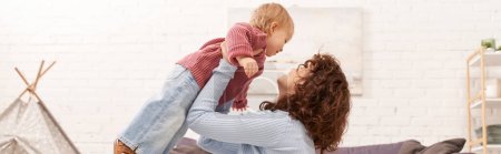Photo for Quality family time, curly woman lifting toddler daughter in cozy living room, work life balance, casual attire, family relationships, modern parenting, loving motherhood, banner - Royalty Free Image