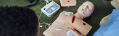 top view of medical instructor holding wound care simulator above CPR manikin and automated external defibrillator during first aid seminar, safety and emergency preparedness concept, banner Poster #661886588