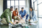 young and multiethnic participants of medical seminar looking at paramedic tamponing wound on simulator with bandage near medical equipment in training room, life-saving skills concept Longsleeve T-shirt #661886720