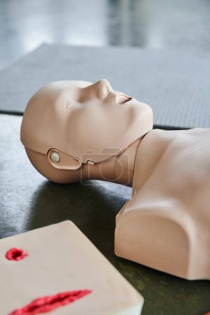 maniquí de entrenamiento de reanimación cardiopulmonar cerca del simulador de cuidado de heridas en el suelo en la sala de entrenamiento, equipo médico para entrenamiento de primeros auxilios y desarrollo de habilidades