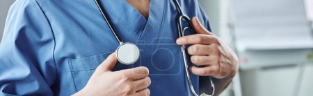 Photo for Cropped view of young healthcare worker in blue uniform, with stethoscope on neck standing in clinic, first aid training seminar and emergency preparedness concept, banner - Royalty Free Image
