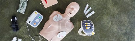 Ansicht des automatisierten externen Defibrillators, Nackenstütze, Spritzen, Kompressionsturnier und Bandagen in der Nähe von CPR-Schaufensterpuppen, medizinisches Gerät für Erste-Hilfe-Ausbildung und Kompetenzentwicklung, Banner
