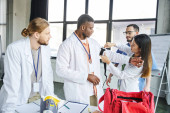 asian woman in white coat applying compressive tourniquet on arm of african american student near instructor, medical equipment and first aid kit, life-saving skills and bleeding prevention concept puzzle #661888132