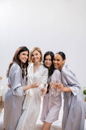 bridal shower, multicultural girlfriends holding glasses with champagne, celebration before wedding, brunette and blonde women, bride and her bridesmaids, diverse ethnicities, looking at camera
