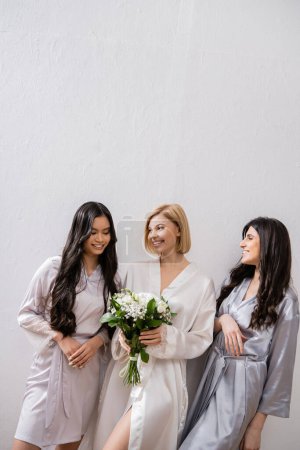 Photo for Happy bride with white flowers, diverse bridesmaids, bridal bouquet, cultural diversity, friendship goals, brunette and blonde women, bridal shower, smile and joy - Royalty Free Image