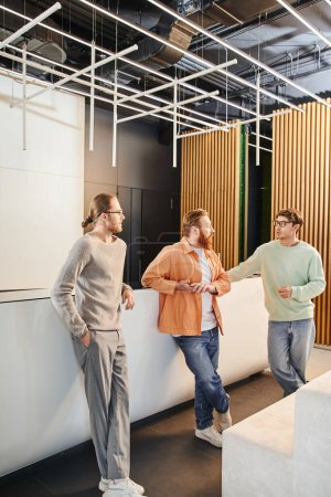 ambitionierte Geschäftsleute in stylischer Freizeitkleidung unterhalten sich bei einem Treffen in der Lobby eines modernen Coworking-Büros mit High-Tech-Interieur, geschäftlicher Zusammenarbeit und Startup-Projektplanung